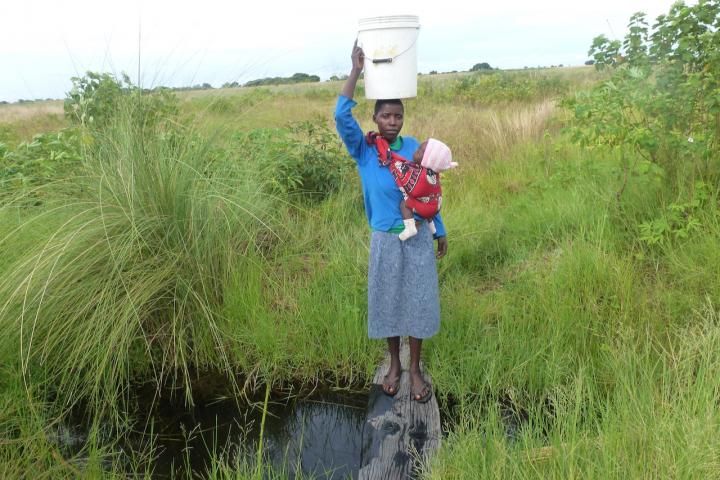 drawing water from an old water source in Suunga Village